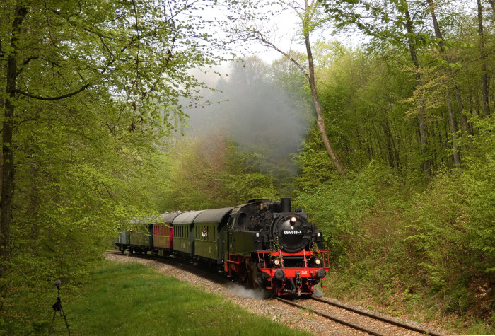 64&nbsp;518 mit Zug von Amstetten nach Gerstetten in der Steigung im Wald kurz vor Stubersheim, um 9:45h am 01.05.2024